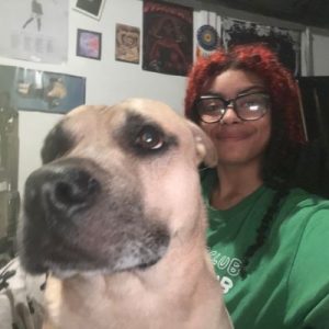 Pet care professional Star smiling at the camera with a large tan dog.